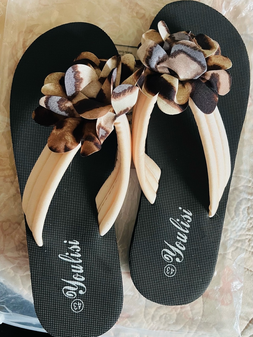 Black Flip Flops with Beige Straps and Floral Accent